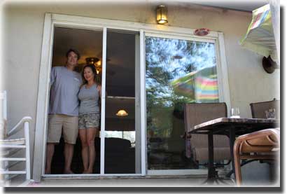 couple standing in doorway of home opening their screen door