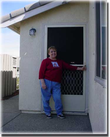 older woman  standing in front of screen door of home