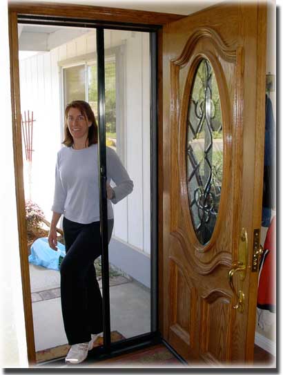 woman in white shirt with black pants standing in doorway of home 