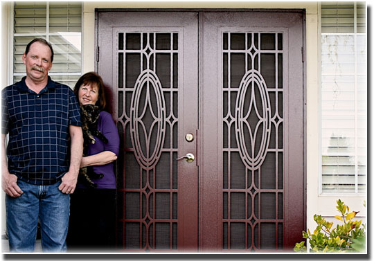 man and woman standing in front of two brown double doors