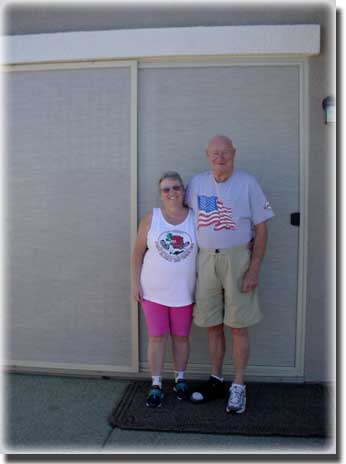 older couple  standing in front of screen door of home