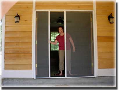 woman standing behind an open screen door from her home to front porch