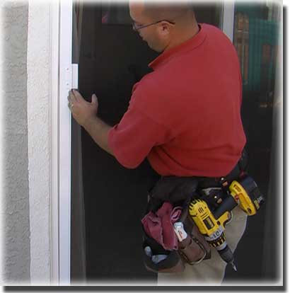 Man in red shirt wearing a tool belt with a drill holding and installing a screen