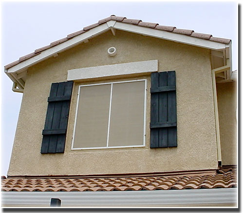 Beige Window Solar Screen in top floor windows of home with black shutters 