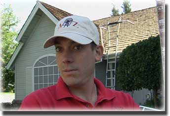 man wearing white baseball hat and red polo shirt standing in front of home with ladder going to roof