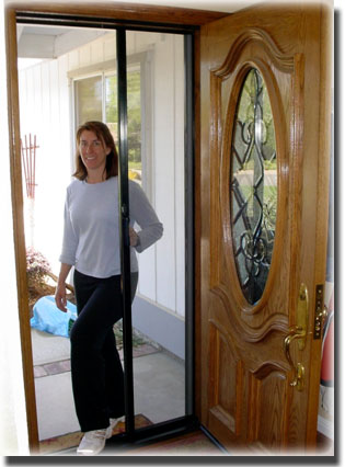 Woman standing in doorway of home beginning to pull screen door shut