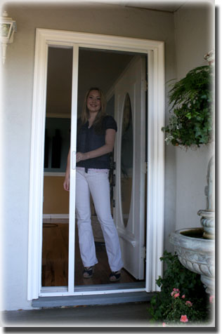 woman closing screen door in front of home