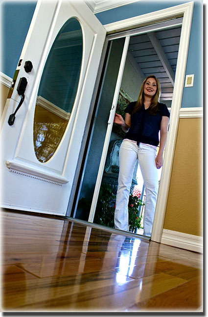 Woman in white pants and black shirt holding the screen door in anen