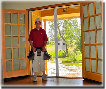 Man in red shirt with tool belt standing in doorway of open French doors