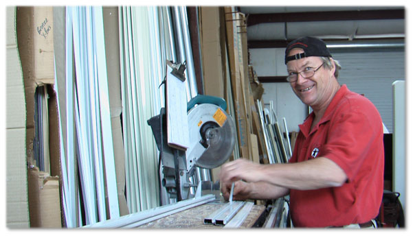 man in red shirt and backwards black basebal hat using a table saw in workshop