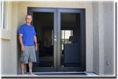 man with blue shirt standing in front of brown double doors