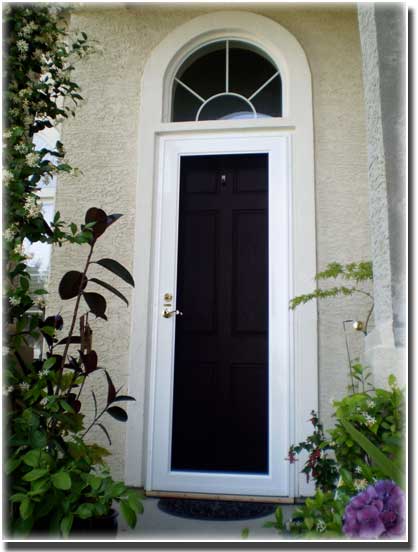 black screen door with white trim and archway with flowers in front on porch