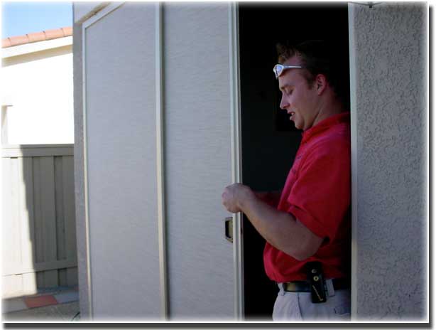 man in red polo shirt with glasses on forehead opening a screen door that he is working on