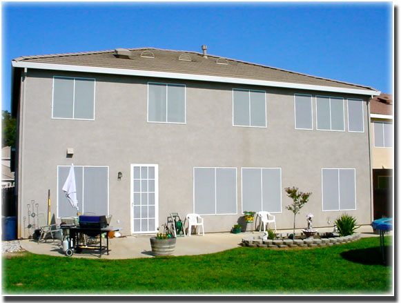 Grey Sun Screens on windows of large two story home with well manicured lawn