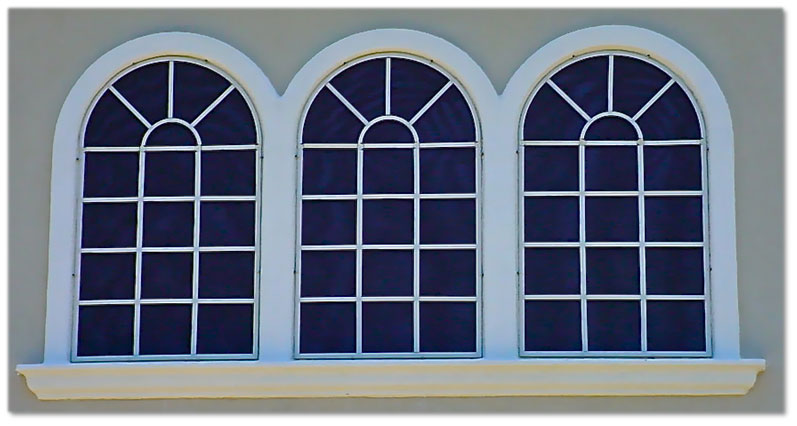 Three arch windows with black sun screens installed