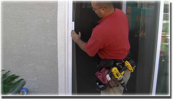 man in red polo shirt wearing a tool belt installed a screen in a door