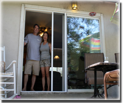 Man and woman standing in doorway of home white chair on porch