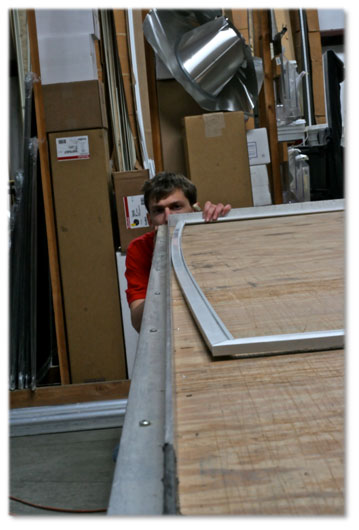 Man crouching and hiding behing wooden pieces in  work shop