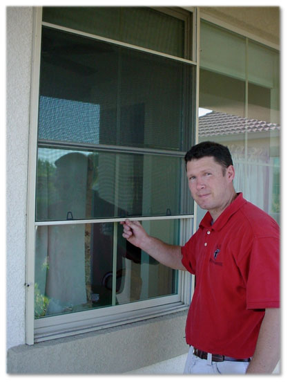 man in red button up shirt pointing to installe window screens in home