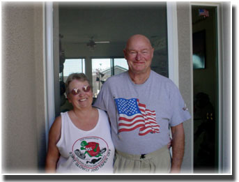 older couple one wearing an American flag shirt standing in doorway of home
