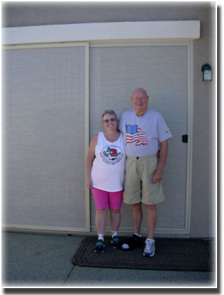 older couple man with a American flag t shirt standing in front  of security doors in their home