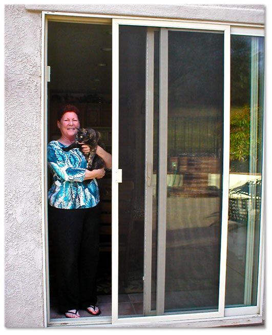 woman holding a dog standing in doorway of sliding glass door