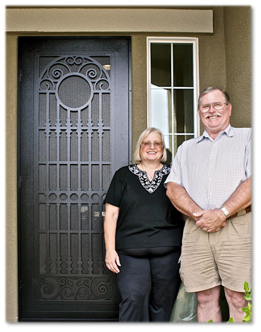Older man and woman standing in front of brown secuirty screen door