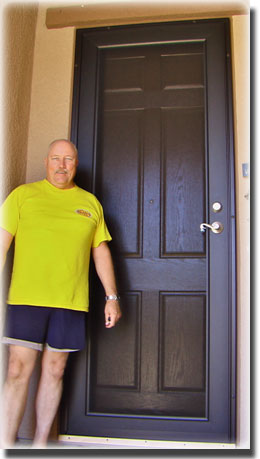 Man in yellow shirt and black shorts standing in front of brown security door