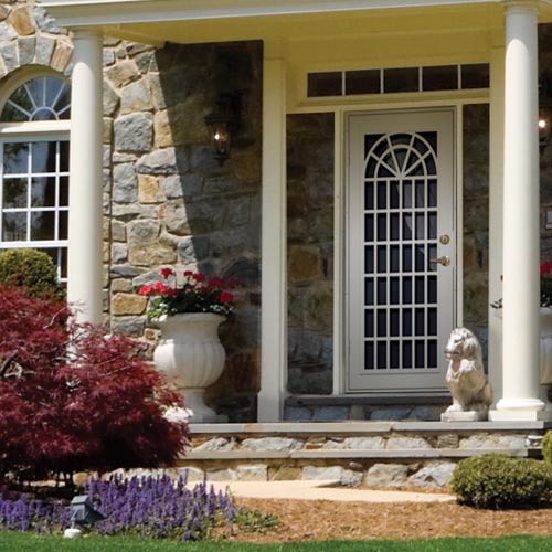 white security door on home with pillars and red and purple plants in front of steps