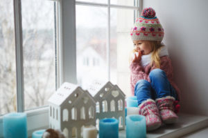 young girl sitting by window in winter