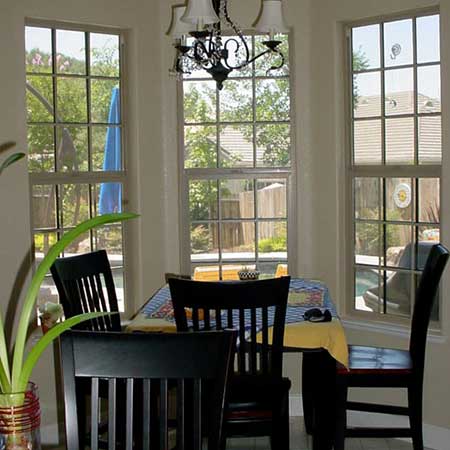 View of out of dining room table and four black chairs looking through three windows with new screen