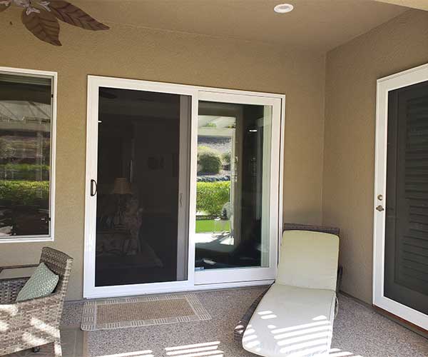 Two sliding glass security doors with white trim and white chairs in front of doors on porch