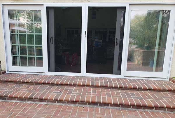 Four Sliding security doors with brick steps in front two doors in the middle are open with screens