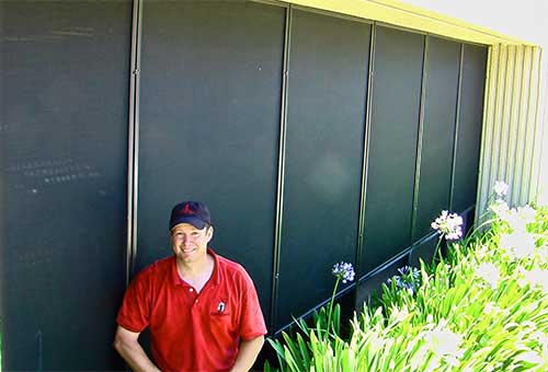 man in red shirt and black baseball hat standing next to metal wall