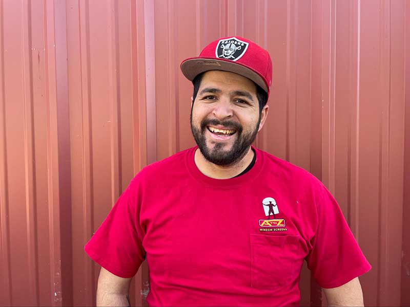 man in red shirt with red raiders hat and beard smiling at camera