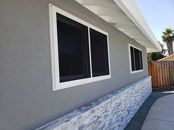 side of home with two sets of black security windows with white trim