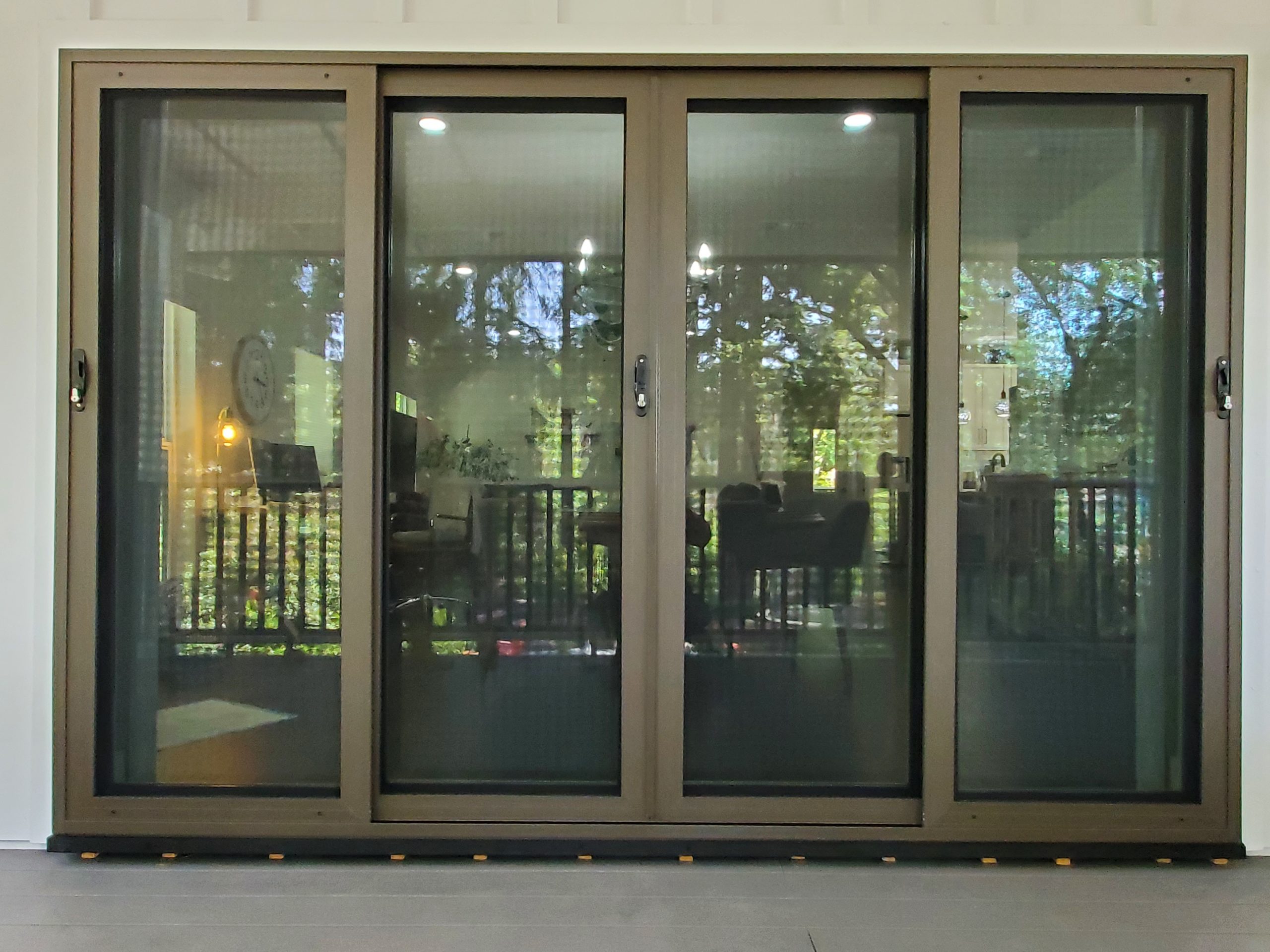 Four Panel French Sliding Secuirty Doors with reflection of front porch railing and trees