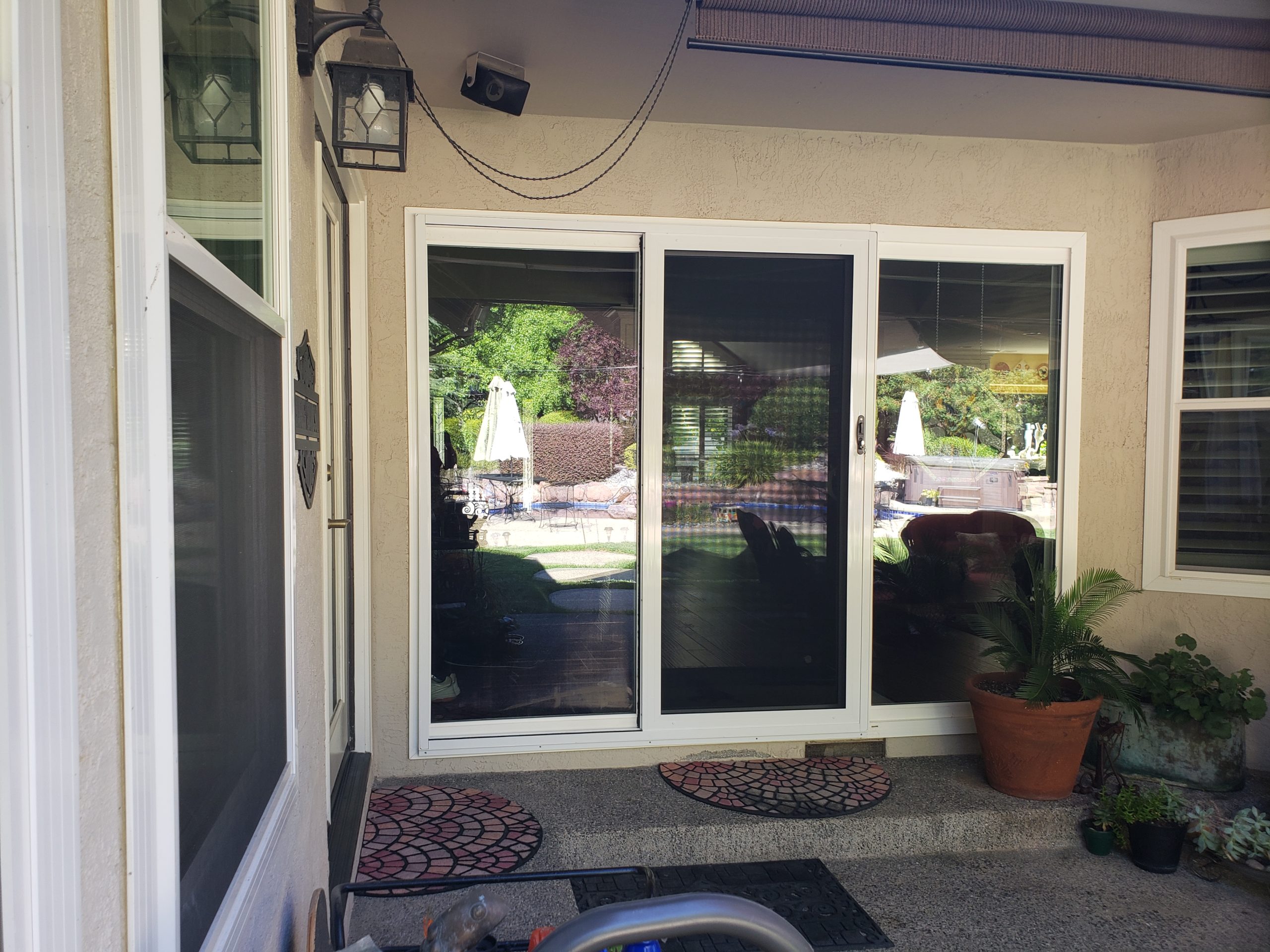 Three sliding security doors we can see a reflection of trees and potted plants in front of doors