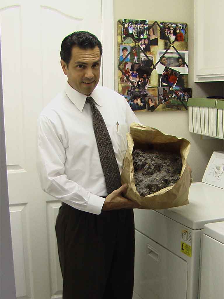 man in white dress shirt and tie holding a brown paper bag filled with dryer vent line